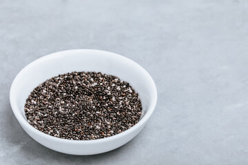 Fototapeta na wymiar Chia seeds. Organic Dry Black and White Chia Seeds in bowl on gray stone background