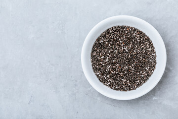 Fototapeta na wymiar Chia seeds. Organic Dry Black and White Chia Seeds in bowl on gray stone background.