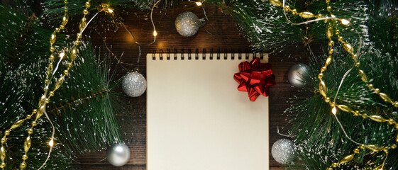 Blank white notebook on dark wooden background with fir branches and silver ball