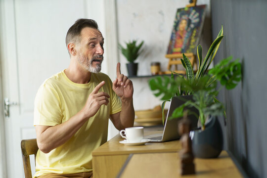 Remote University Mature Student Taking Distance Classes. Focused Handsome Beard Man Sitting At Desk At Home With Laptop Computer, Gesturing On Video Meeting. Remote Education, Studying Online Concept