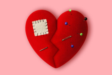 Broken heart with pins, sewing needle and patch on pink background - Concept of healing a broken heart
