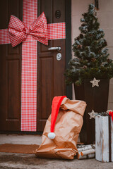 Christmas decoration of the porch of the house. The entrance door is decorated with a large red bow.