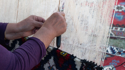 Women's hands knit carpet on a loom, textile industry