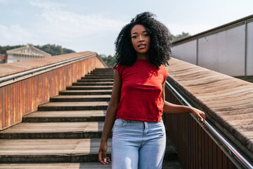 Cheerful ethnic woman walking on wooden stairs