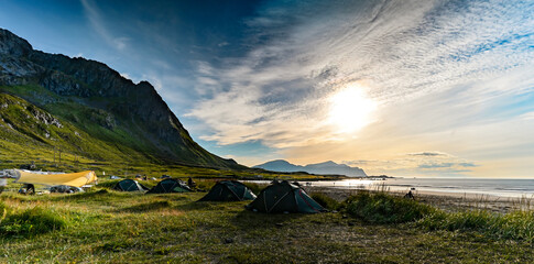 Eine Gruppe Menschn zeltet mit ihren Zelten auf den Lofoten am Strand bei Sonnenuntergang