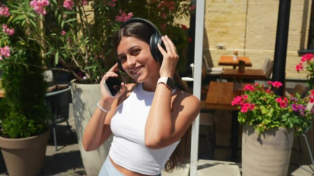 Young woman listening music with wireless headphones in the street