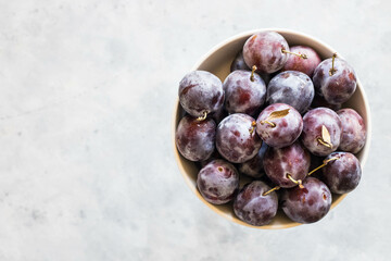 Fresh purple fruit plum on a metal plate on a light background, top view. Close-up.