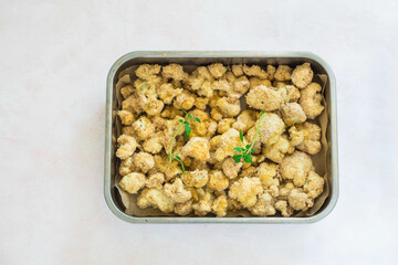 Cauliflower baked in breadcrumbs on a light background, close-up, top view, selective focus, no people.