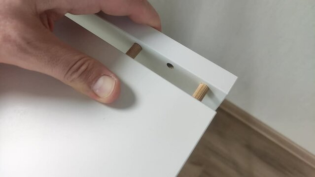 	
Furniture assembler connects pieces of furniture boards with wooden dowels	

