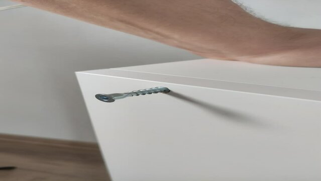 Vertical video. Furniture assembler connects parts of furniture boards with confirmat and hexagon	