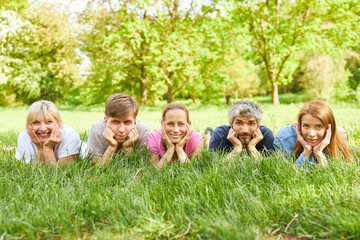 Obraz premium Five friends lie side by side on the grass