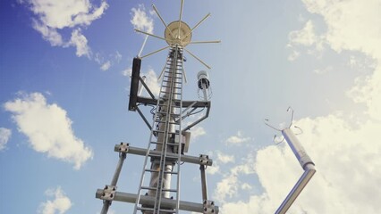 Weather and communication antenna under blue sky - camera pans slowly low angle. Tall tower with various devices and equipment for weather measurements and data and media communication - Powered by Adobe