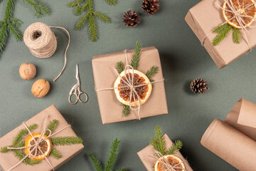 Boxes, craft paper, twine, scissors, dried oranges and natural decor for wrapping XMAS, New Year gifts on green background. Concept Zero waste Merry Christmas. Top view Flat lay