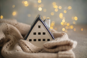 Ceramic house insulated by warm sweater. Concept of protection of house and lack of heat at home in winter