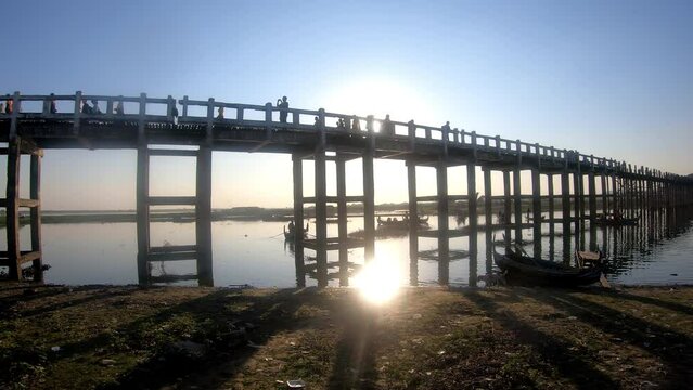 The setting Sun reflecting in the Water at U Bein Wooden Foot Bridge build around 1850 at Amarapura