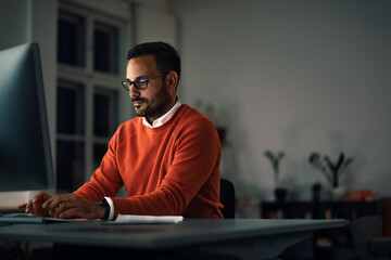 The concentrated man sitting and working online, at night.
