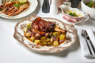 baked duck leg with stewed vegetables in sweet and sour sauce on a plate top view
