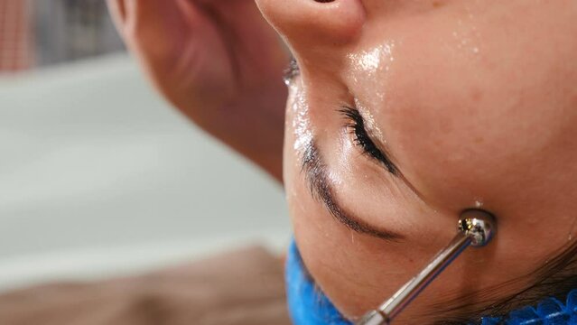 Vertical footage. Myostimulation cosmetic care. Treating facial muscles using electric current. Hardware cosmetology equipment. Beautician making microcurrent lifting procedure on face. 4 k video