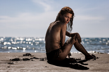 Fototapeta na wymiar Sexy girl sitting on a beach. Body covered with sand.