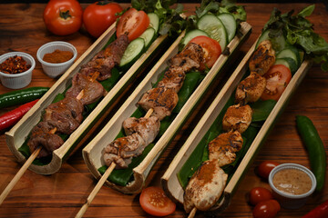 Tasty grilled meat with Sichuan pepper in bamboo barrel plate and vegetable on rustic wooden table