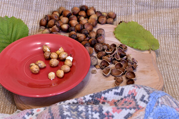 Hazelnut fruits on a plate with green leaves.