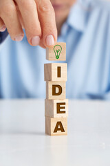 Businesswoman holding wooden block with light bulb on it. Idea concept.