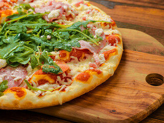 Top quality uncooked Italian pizza with spinach and meat on a wooden tray and table. Cook at home product. Top range ingredients. Classic meal. Close up. Selective focus.
