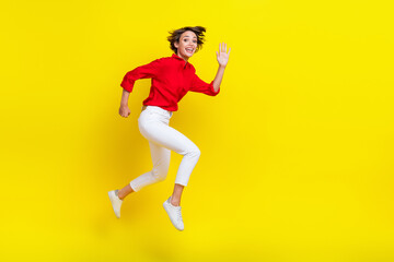 Full size profile photo of energetic cheerful girl hurry jump arm wave hi isolated on yellow color background