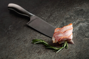 Bacon with rosemary on a kitchen knife.