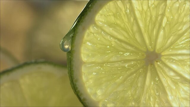 Drop of Lime Juice flow down the surface of a ripe juicy Lime slice. Slow Motion 4K