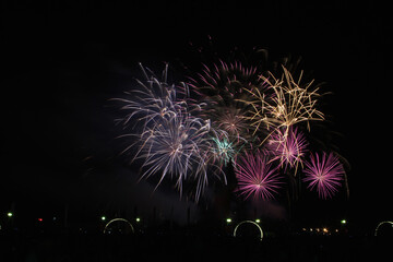 Multicolored fireworks in the dark sky, city day celebration.