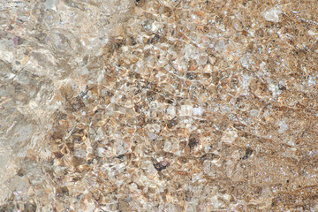 Top view of pebble stone beach on the ground with transparent water of sea serving above