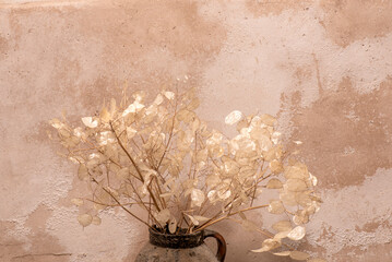 Cántaro con ramo de flores secas, pared al fondo con texturas
