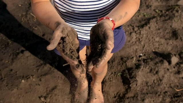 The child holds the soil in his hands. Selective focus.