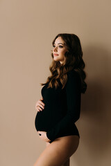 Young pregnent woman in lingerie posing isolated on a beige background