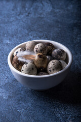 Quail eggs in a white bowl on a dark background