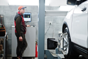 Fototapeta na wymiar Auto mechanic sets american SUV car for diagnostics and configuration camber check in workshop of service station..