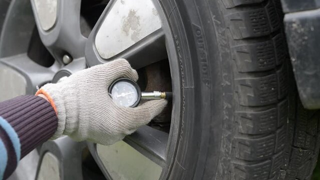 Measuring the pressure in the tires of a car with a pressure gauge.