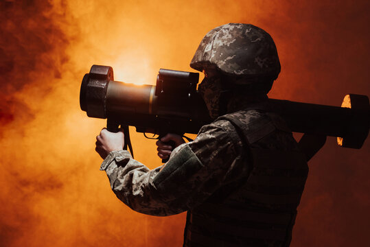 Military missile, combat, combat, war, big gun shooting. Action. Silhouette of a military soldier firing a grenade launcher. studio shot with colour orange  smoke  - Powered by Adobe