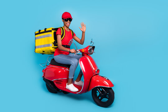 Photo of friendly funky short hair human wear red uniform moped rider fast food delivery waving arm isolated blue color background