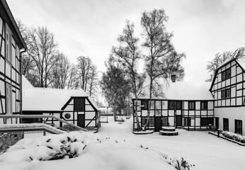 Historic factory village panorama “Maste-Barendorf“ with truss buildings in Iserlohn Sauerland Germany on a cold winters day. Touristic Museum and sight covered with snow, black and white greyscale. - Powered by Adobe