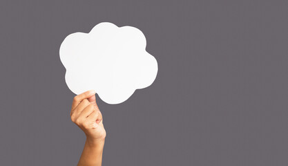 Close-up of hand holding a white speech bubble cloud against a gray background