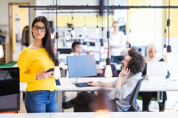 Creative team of young successful people in a modern office. Portrait of a beautiful female coworker wearing glasses.