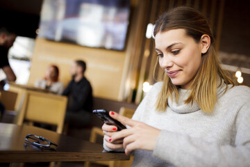 Girl at a modern cafe looking at phone.