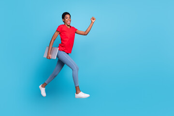 Fototapeta na wymiar Photo of cute charming short hair person dressed red t-shirt hurrying jumping carrying modern gadget isolated blue color background