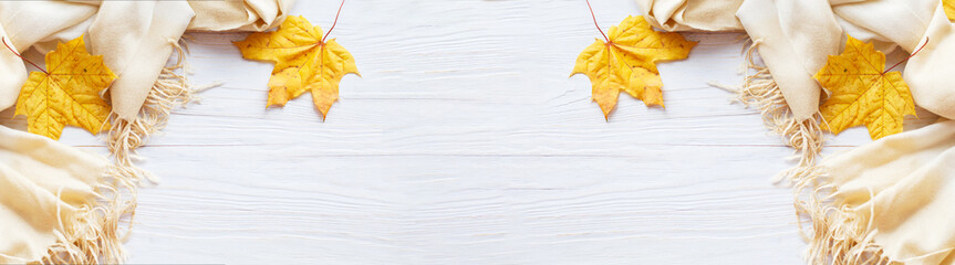 autumn leaves with a scarf on a wooden background with copy space. banner