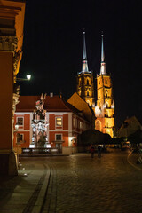 nocne zdjęcie starych kamienic i wież kościoła we Wrocławiu