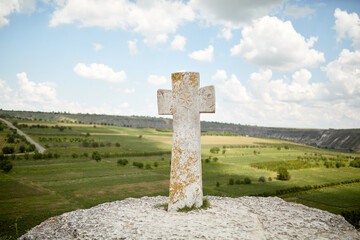 Fototapeta na wymiar cross stone monument on hill against a panoramic view of the canyon