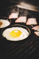 chef cooking Eggs and bacon in pan on grill in kitchen