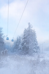 Obraz premium Bansko, Bulgaria winter ski resort with blue gondola lift cabins, forest pine trees and mountains view